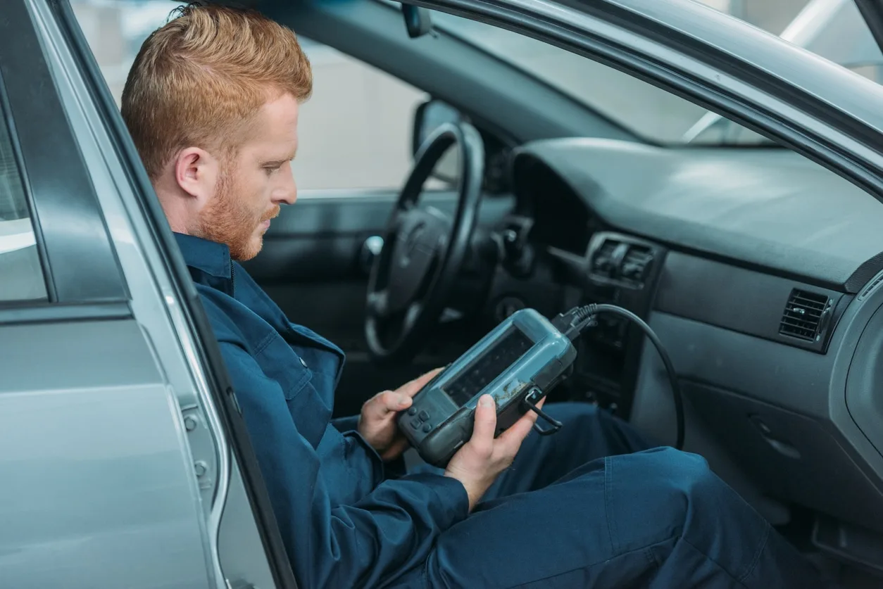 Mechanic using a handheld vehicle diagnostic scanner